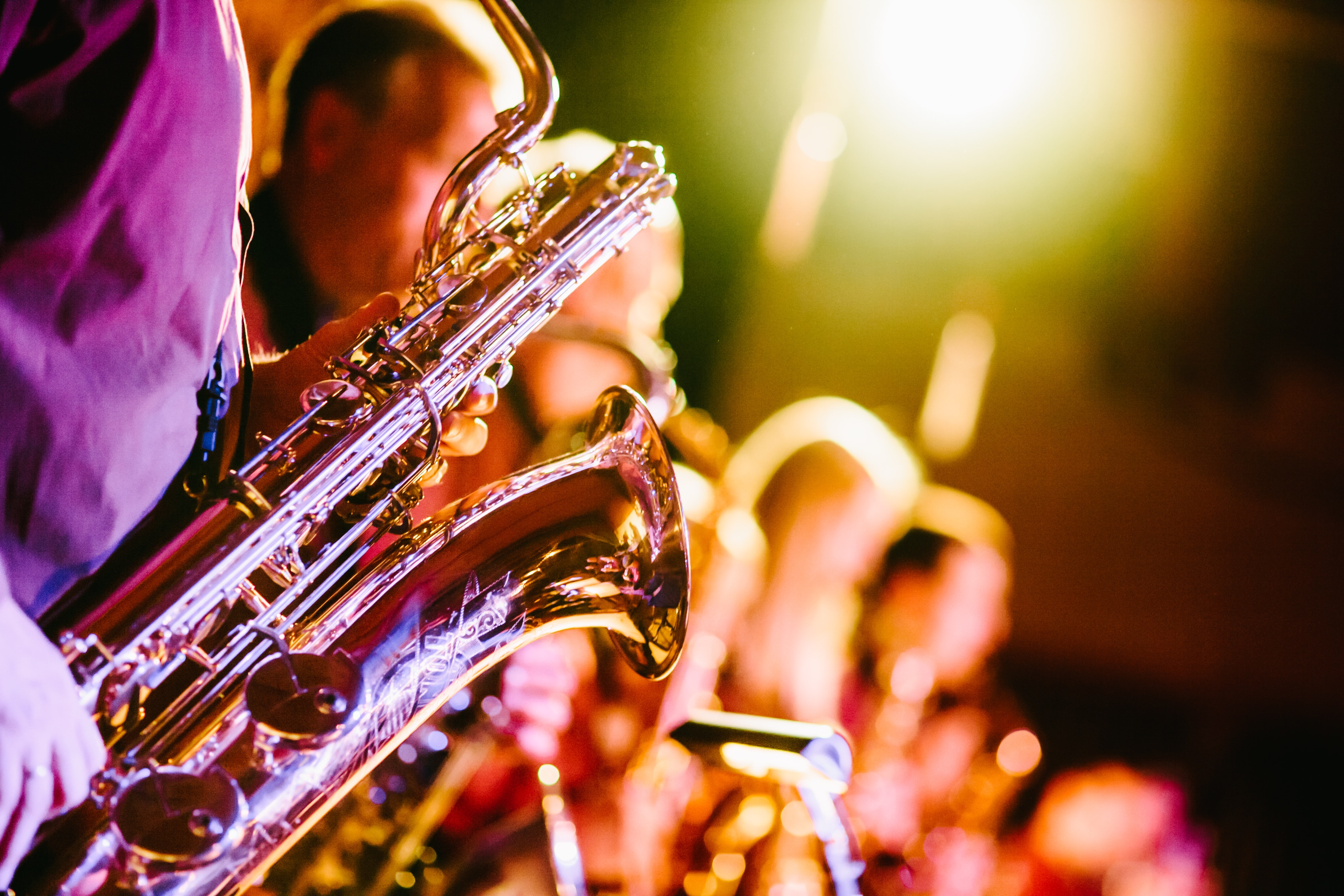 A saxophone featured in the foreground of a line of people at a musical performance event